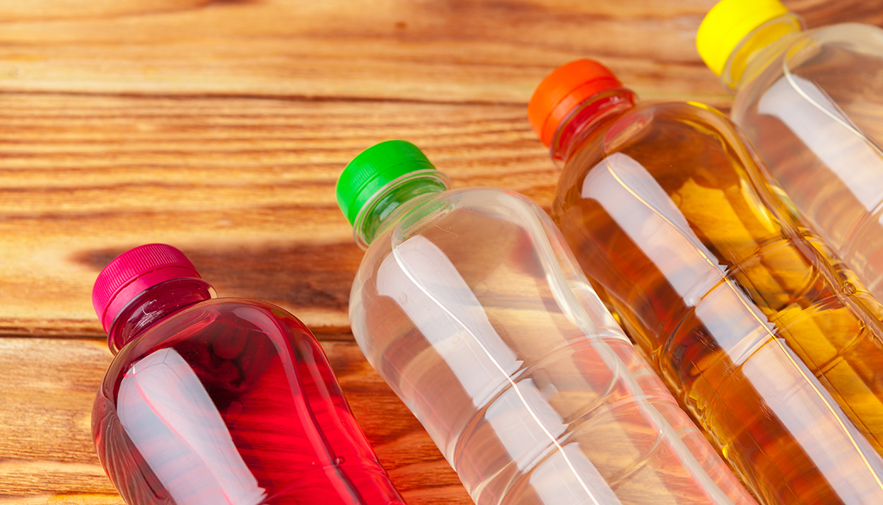 plastic bottles with soft drinks background close up
